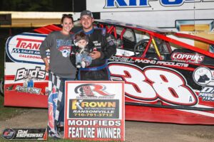 A family of three standing in front of a race car 