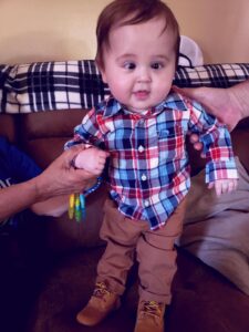 A baby standing on a couch. 