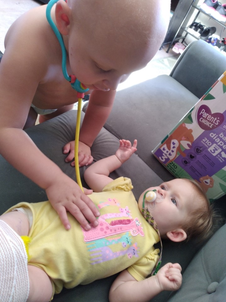 A toddler checks the heartbeat of a baby with a toy stethoscope